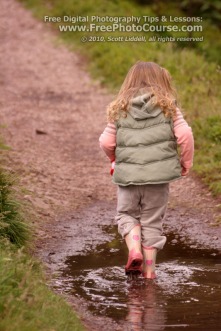 Picture of a child walking through a mud puddle with reflection of feet and legs.  Visit www.FreePhotoCourse.com for free digital photography tips, lessons and more.