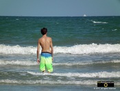 Picture of a boy in board shorts at the beach, watching the ocean surf.© 2011, FreePhotoCourse.com, all rights reserved.  Awesome beach pictures & wallpapers. Download free jpg, jpeg photos.  