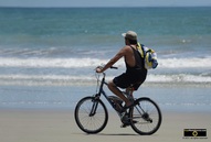 Interesting picture of a man with a backpack, riding his bicycle on the beach.© 2011, FreePhotoCourse.com, all rights reserved.  Awesome beach pictures & wallpapers. Download free jpg, jpeg photos.  