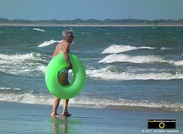 Picture of an elderly woman holding a green swimming tube at the beach. © 2011, FreePhotoCourse.com, all rights reserved.  Awesome beach pictures & wallpapers. Download free jpg, jpeg photos. 