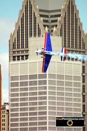 Picture of a stunt plane flying past downtown city skyscrapers.© 2011, FreePhotoCourse.com, all rights reserved.  Free high-res desktop wallpapers and pictures.  