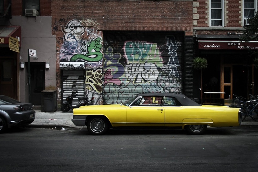 Picture of a yellow rag top muscle car parked in front of a heavily 'decorated' wall and garage door in the East Village, NYC; shot by Stan Baranski; part of the www.FreePhotoCourse.com New York Photo Exhibit 'NYC Exposed'; all rights reserved 