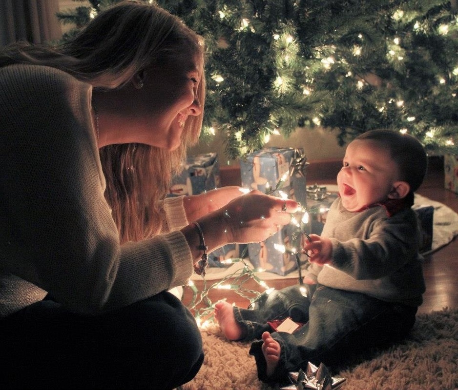 Christmas picture - A new mom and her smiling infant playing with a string of Christmas lights under the tree.  Photo Credit: Rachel Rawlins.  Featured in the December 2011 Contributors' Gallery from FreePhotoCourse.com.  all rights reserved, © 2012. 